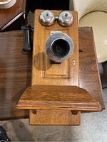 Front view of the oak wall mount telephone showing two metal bells and large mouthpiece.