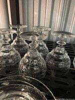 Six goblet style glasses upside down showing faceted stems and thick bases.