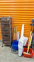 Wide view of all cleaning and storage items including storage rack, mop bucket, dolly, garden fabric, blinds, squeegee, buckets, and cleaning brushes.
