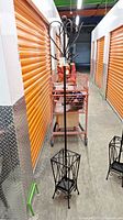 Full view of tall black metal coat rack with umbrella stand base, showing entire item standing upright.