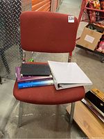 Red fabric office chair with books and a white binder placed on seat