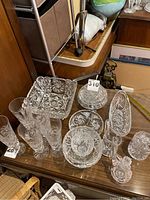 Full collection of crystal glassware displayed on wooden table showing various pieces including bowls, pitchers, and glasses.