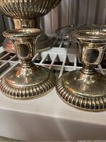 Close-up image of two ornate silver plated candle holders with detailed bases showing some tarnish