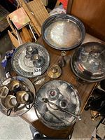 Various silver plated items displayed together showing trays, candle holders, napkin rings, a covered dome, and small containers; some heavily tarnished