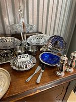 Photo displaying two-tier serving tray, clam shell serving dishes, salt and pepper shakers, scalloped serving plates, and knives.