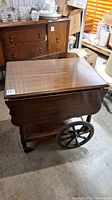 Side view of vintage wooden tea cart showing closed top and large wooden wheels.