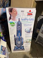 Front view of the boxed Bissell vacuum cleaner showing branding, model, and woman image on the packaging.