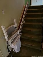 Full view of the white Concord Liberty stairlift chair with track mounted along a carpeted straight staircase, showing the foldable seat and footrest.