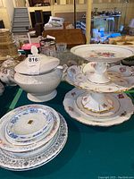 White ceramic soup tureen with lid and various plates arranged on a table with background basement items visible