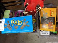 Top-down shot showing blue Furby box and yellow Kodak Brownie camera box side by side