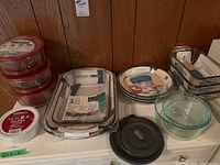 Overview of Pyrex bowls with vented lids, glass bakeware sets including Anchor Hocking dishes, CorningWare dish, and other baking dishes on counter.