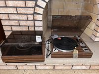 Photo shows two turntables with wood grain style bases and plastic dust covers, one opened showing the tonearm and control panel labeled Taya CP-250.