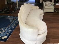 Side angle showing curved shape, tufted back, and upholstery condition of vintage couch.