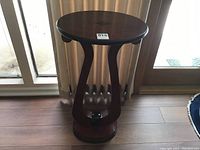 Full view of the round Biedermeier style table showing the curved wooden lyre supports and base with artificial plant.