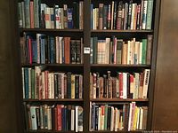 Full view of wooden bookshelf with four shelves filled with assorted books
