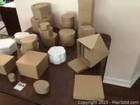 Multiple craft boxes in assorted brown and white colors on a table, showcasing a mix of shapes like round, hexagonal, and flower-shaped boxes.