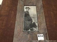 Full view of the etched stone artwork showing the cypress tree on a cliff with ocean in the background framed in stone.