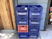 View of stack of blue Dean's plastic crates with two red Sealtest crates in the middle, showing advertising logos and condition
