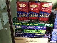 Boxes of various new holiday string lights including Holiday Living 100 Light Clear bulbs, Blue light set, Westinghouse 100 light sets, Super Bright String-A-Long, and Flicker Flame lights.