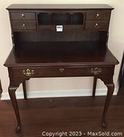 Front view of the dark wood secretary desk with five drawers and three cubbyholes at the back.