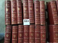 Photo showing maroon leather-bound Harvard Classics volumes with gold embossed lettering and Harvard shields on spine.