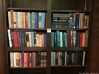 Wooden bookshelf with four shelves of assorted hardcover books