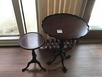 Full view of both vintage mahogany side tables, showing their relative size and tripod claw-foot bases.