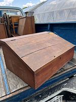 Slant top desk viewed from the front left side on truck bed, showing angled writing surface and dovetailed corner