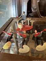 Set of four Beatles figurines displayed on glass surface with reflections. Includes drummer and three guitarists.