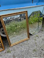 Both large mirrors with different shapes and frame styles outside against a blue vehicle.