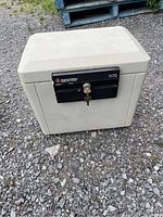 Off-white Sentry 1170 safe closed with key in lock visible outside