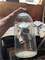 Jar held in hand showing embossed beaver design and 'RIVERV' on the glass side
