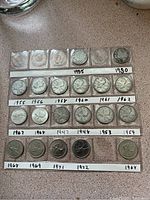 Photo showing front rows of Canadian quarters with dates labeled 1935, 1930, 1955, 1956, 1958, 1960, 1961, 1962, 1967, 1968, 1947, 1948, 1953, 1959, 1968, 1969, 1971, 1972, 1968, arranged in a display tray.