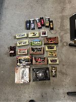 Top-down view of complete lot of untaken die cast cars, engine model, bobblehead, and mini hockey sticks on concrete floor