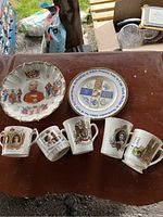 Shows a collection of 2 decorative plates and 5 commemorative mugs with royal family imagery and text.