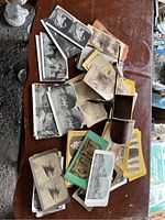 Photo showing a table with a pile of vintage stereograph cards and the wooden stereoscope viewer.