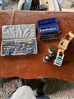 Top-down image of the entire lot on a brown wooden surface showing all drafting tools, pens, nibs, and ink bottles.