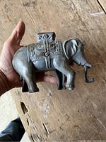 Side view of vintage cast metal elephant bank showing decorative details and keyhole for coins.