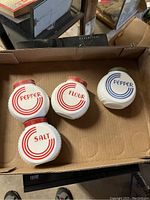 Four vintage milk glass Hoosier jars: Pepper (red lid), Flour, Salt, and Pepper (blue text) in box.
