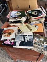 Stacks of over 150 vintage 45 RPM vinyl records in paper sleeves, some with visible album covers including Sting and The Who