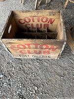 Wooden vintage Cotton Club ad box showing red and black lettering, inner dividers for bottles visible, aged wood finish.
