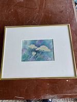 Framed watercolour artwork showing entire painting with mat and gold trim frame on a wooden surface.