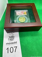 Closed wooden display case with glass top showing PCGS slab inside
