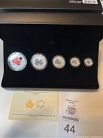 Black display case open showing five silver coins in capsules and certificate card