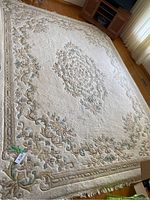 Wide shot of entire rug on hardwood floor showing central medallion and floral border