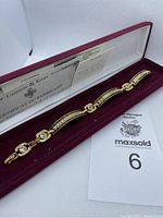 Gold-tone black jeweled bracelet in burgundy presentation box with certificate of authenticity