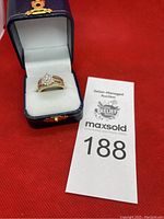 Ring in navy presentation box on red background with auction lot card visible