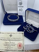 Brooch and bangle displayed in their original Camrose & Kross boxes with certificate of authenticity.