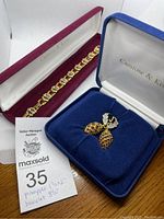 Photo showing both the pineapple brooch and the bracelet in their original boxes with dealer tag including handwritten sizes.