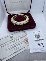 Bangle displayed resting on burgundy velvet case with Camrose & Kross branding and authenticity certificate included.